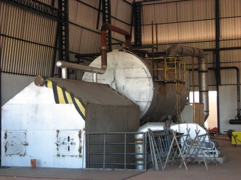 Caldeira industrial de grande porte instalada em galpão, com fornalha e dutos de exaustão