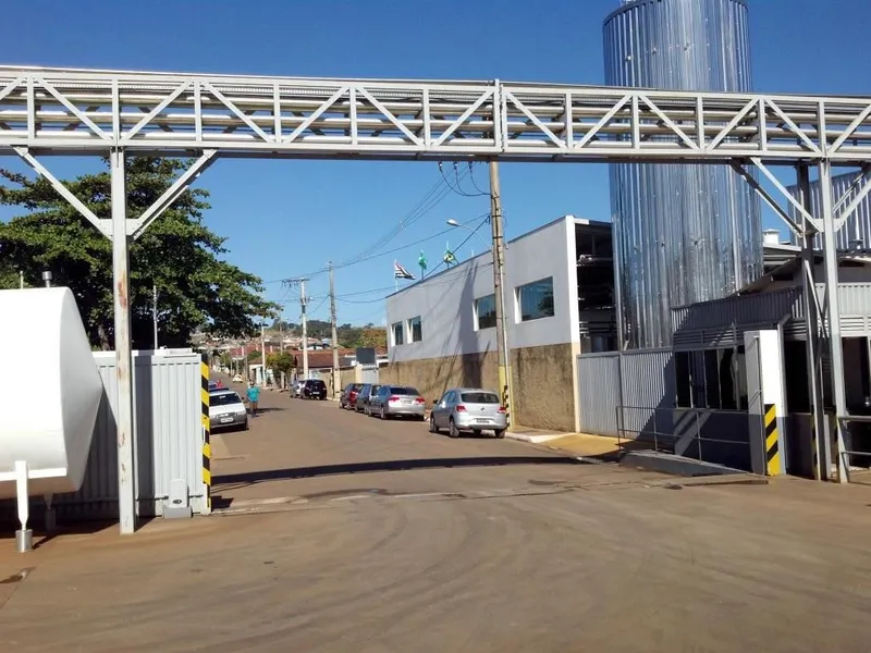Estrutura metálica treliçada elevada para suporte de tubulações cruzando via de acesso em planta industrial
