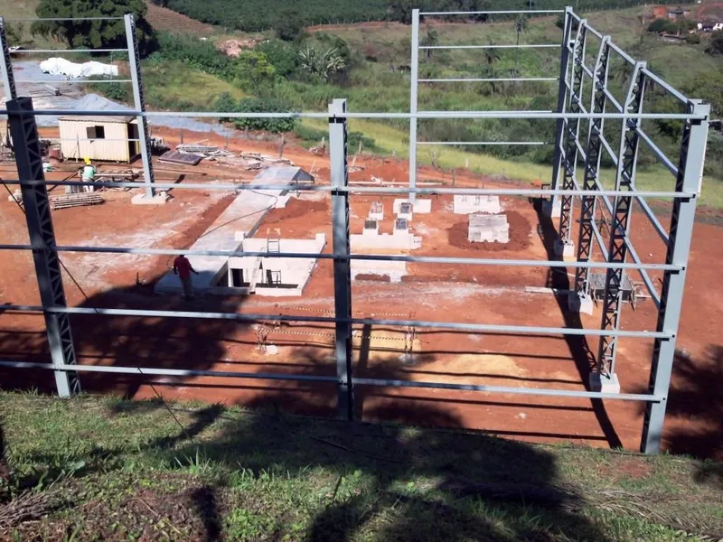 Colunas e estrutura metálica de galpão em montagem sobre fundações de concreto em canteiro de obras