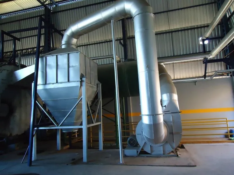 Sistema de exaustão industrial com ciclone, ventilador centrífugo e chaminé dentro de galpão