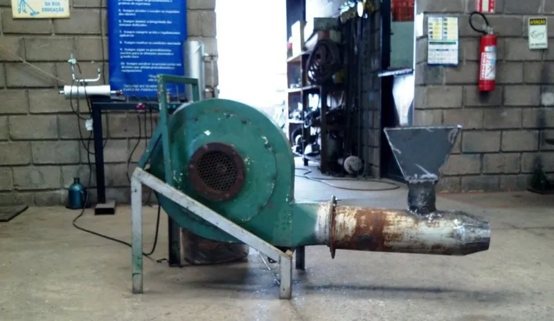Exaustor centrífugo industrial com silencioso acoplado, posicionado no piso de oficina de manutenção